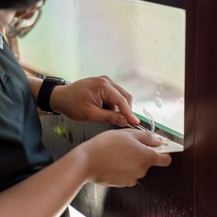 Close view of a blade trimming protective film flush to a panel edge