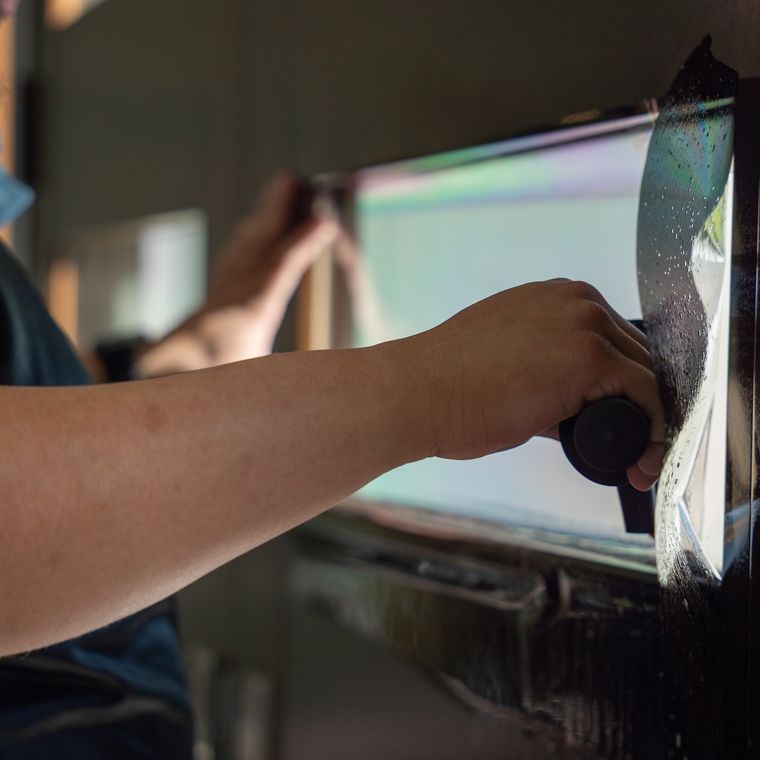 Installer drawing a sheet of protective film across wet glass
