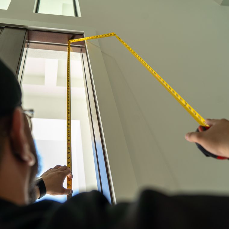 Installer measuring a window opening with a tape measure before any film is cut