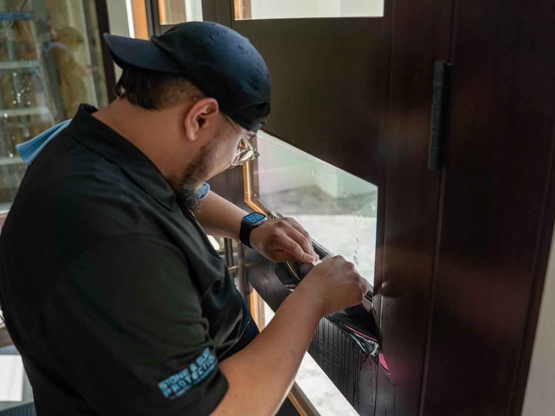 Installer working protective film down against a door frame