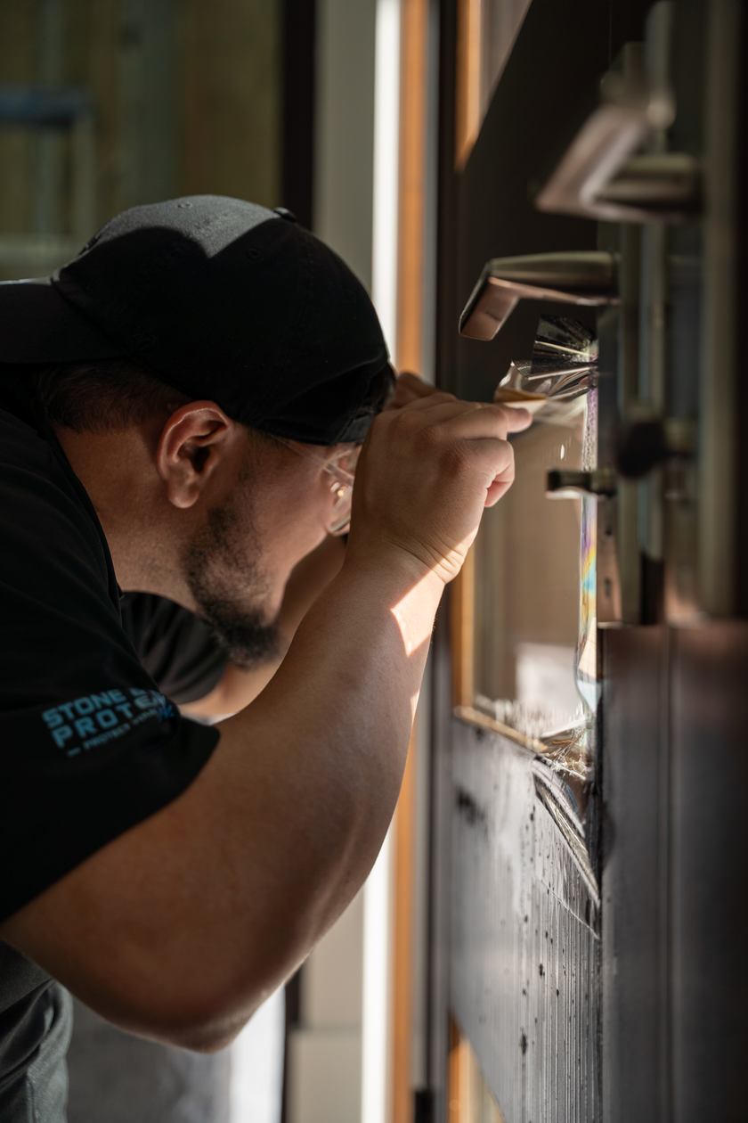 Installer working protective film around a door handle