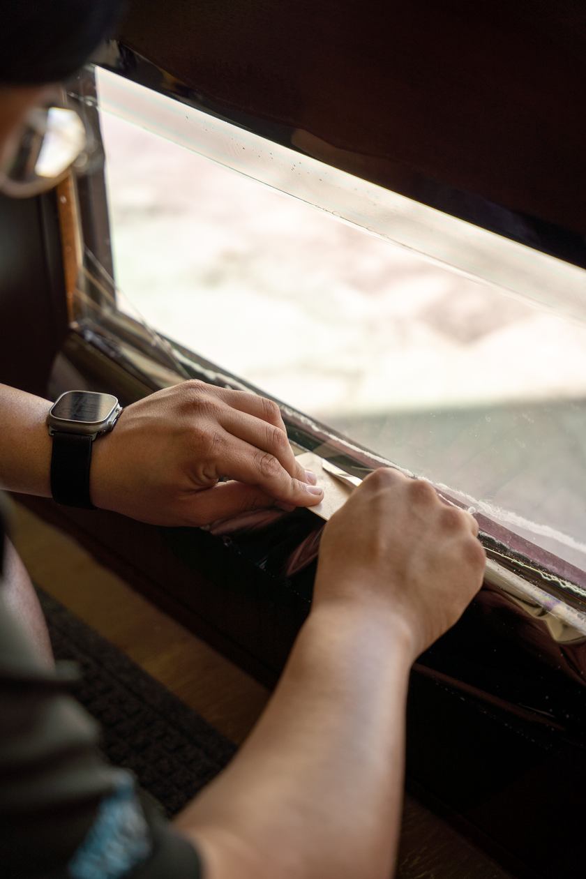 Installer finishing protective film along the lower edge of a pane