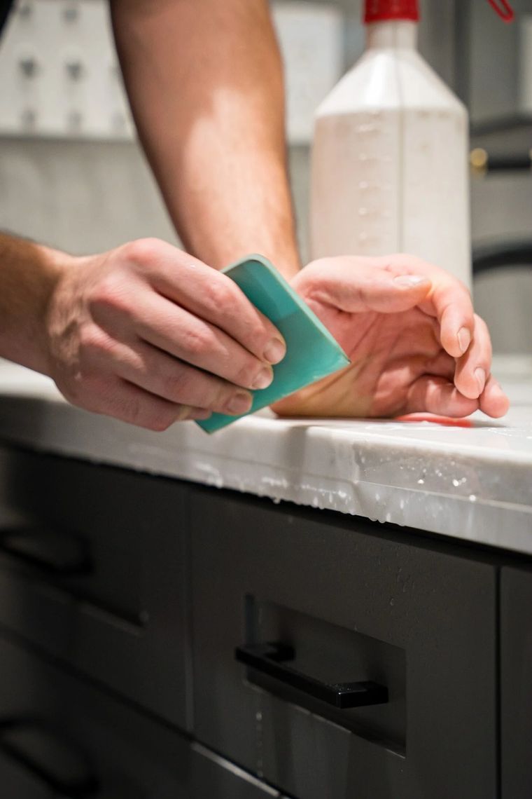 Installer working a squeegee across protective film on a white stone countertop