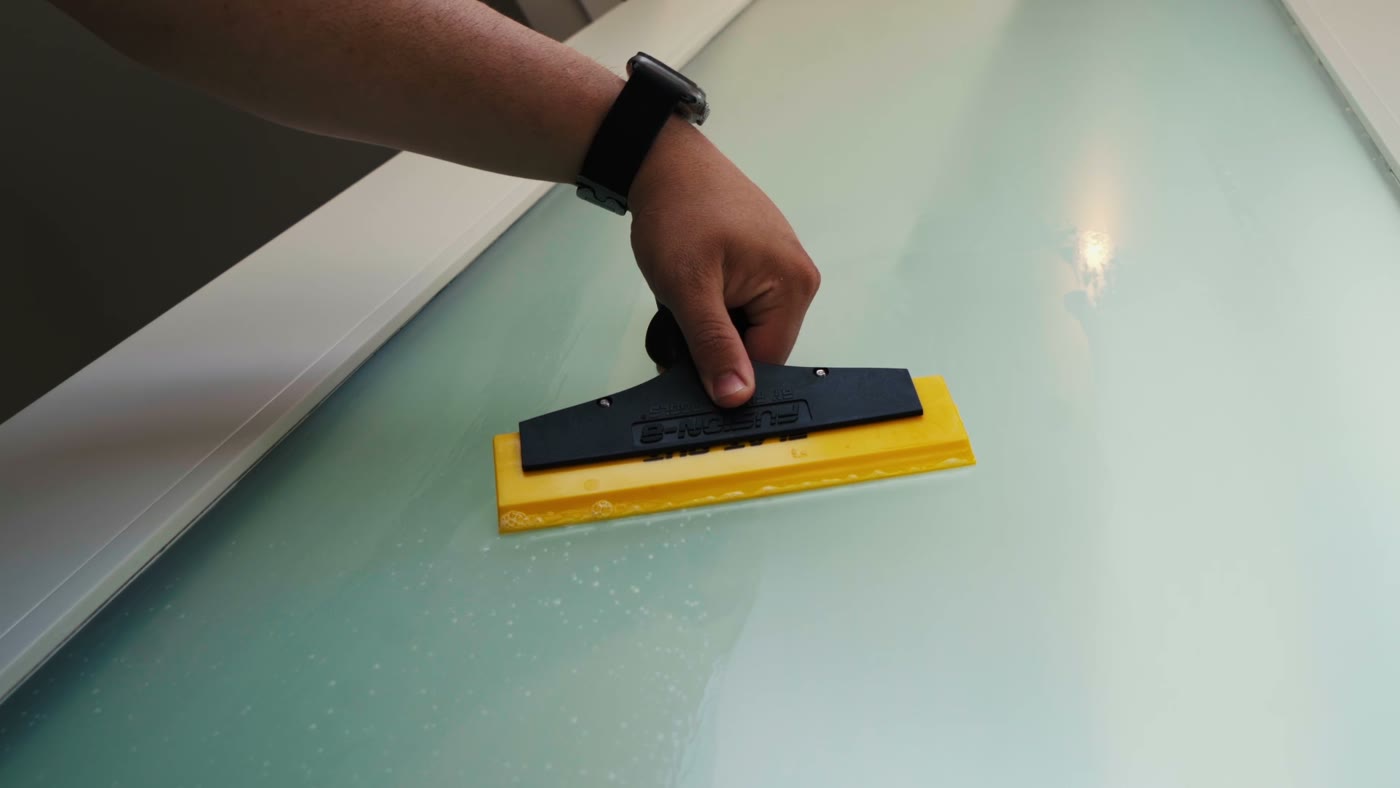 Squeegee pass across a filmed tabletop surface