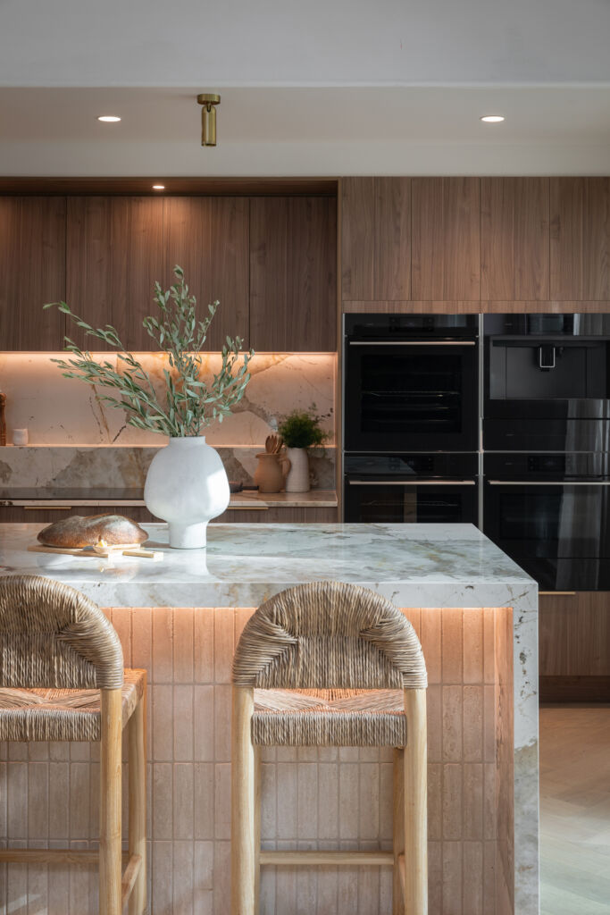 Marble waterfall kitchen island with walnut cabinetry and stone backsplash