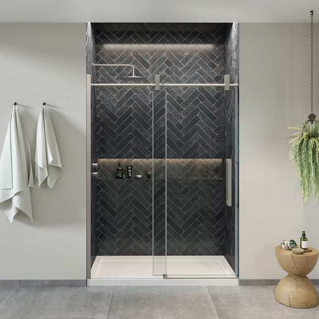 Frameless glass shower enclosure with dark herringbone tile